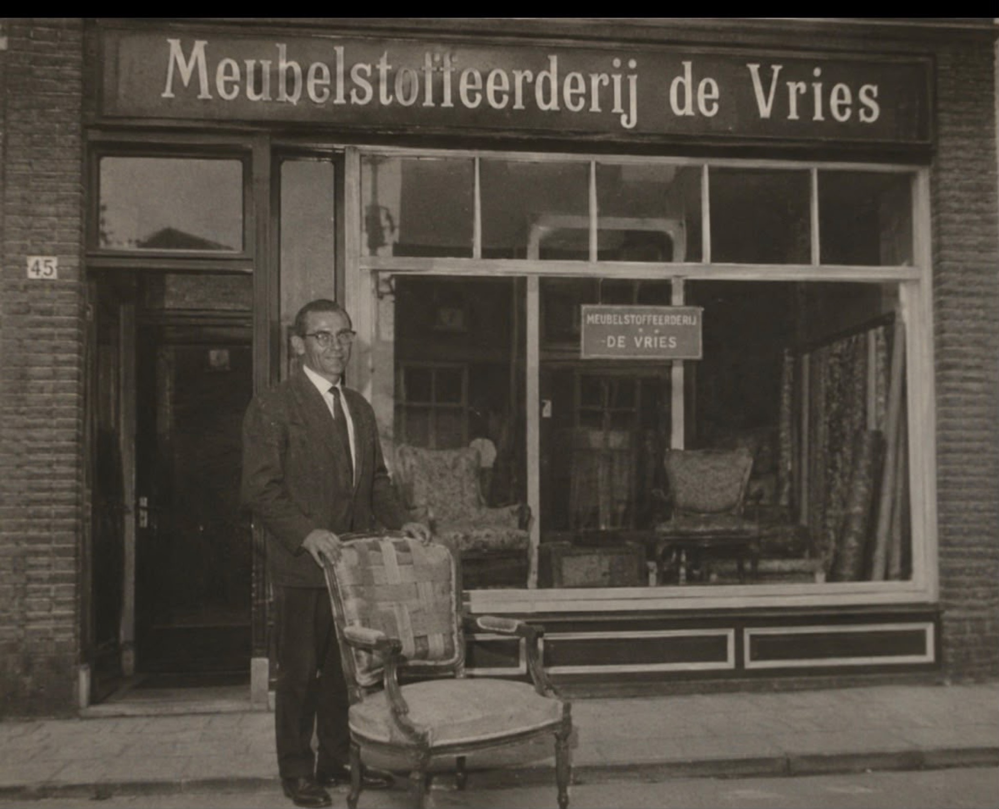 Historische zwart-witfoto van opa De Vries met een fauteuil voor zijn meubelstoffeerderij